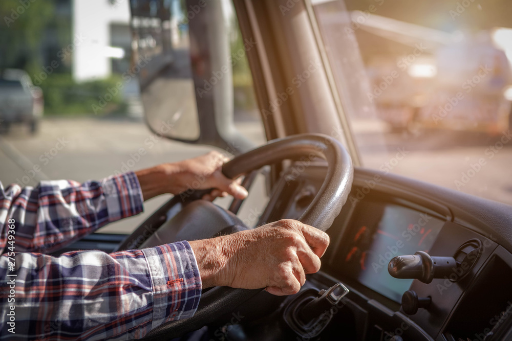 Truck driver keeps driving with one hands and change gears,The man Behind Semi Truck Steering Wheel,spot focus. - obrazy, fototapety, plakaty 