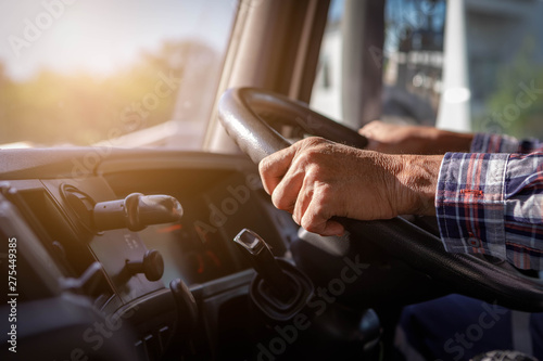 Truck driver keeps driving with one hands and change gears,The man Behind Semi Truck Steering Wheel,spot focus.