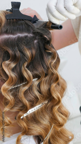 Hairdresser hands curling hair with silver clips in the salon. 