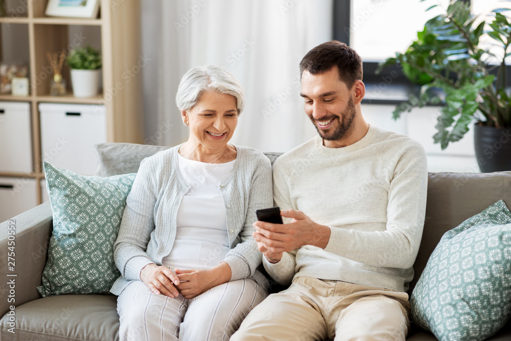 family, generation and people concept - happy smiling senior mother and adult son with smartphone networking at home