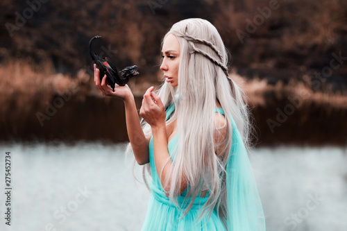 The girl holds in front of her on the hand of a small dragon look at each other model of Asian appearance with white hair