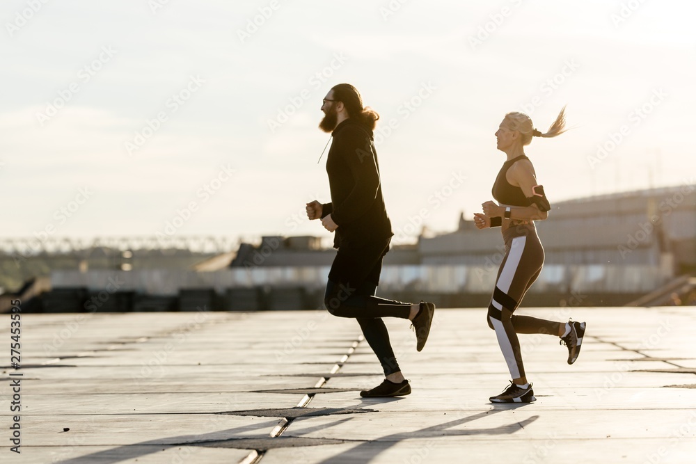 Bearded man with a girl on an evening jog in the open air running after each other on the waterfront Bearded man with a girl on an evening jog in the open air running after each other on the waterfront