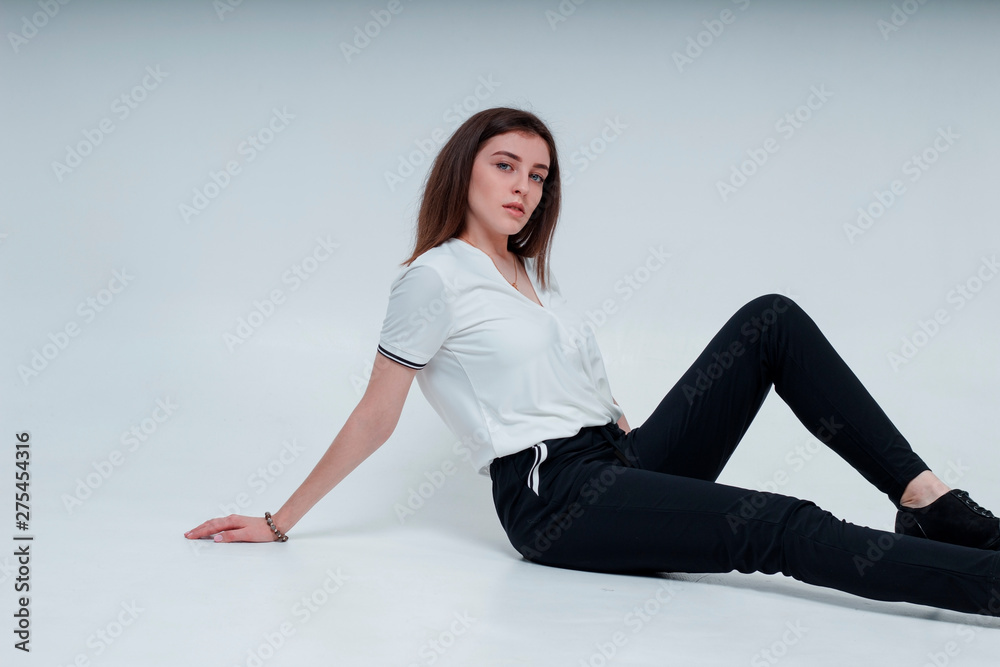 Beautiful young glamor girl sits on a white background in the studio Beautiful young glamor girl sits on a white background in the studio