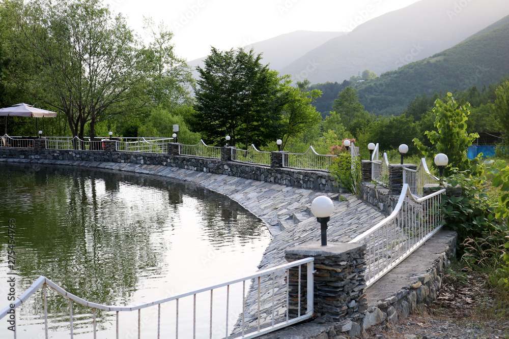 The lake with iron fence is surrounded by mountains in Shaki, Azerbaijan