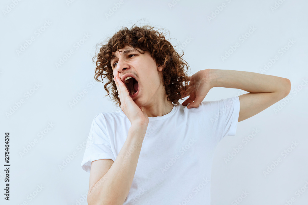 Tired,boredom and exhausted emotion. Yawning Curly teen guy portrait against white background Tired,boredom and exhausted emotion. Yawning Curly teen guy portrait against white background