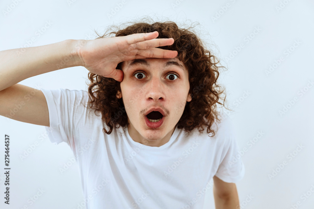 Surprised,shock ,unbelievable emotion. Curly teen guy face portrait agaist white backgraund. Surprised,shock ,unbelievable emotion. Curly teen guy face portrait agaist white backgraund.