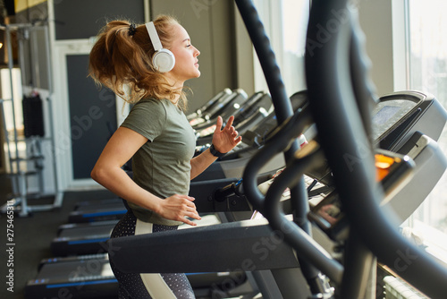 Girl in headphones running on the treadmill.