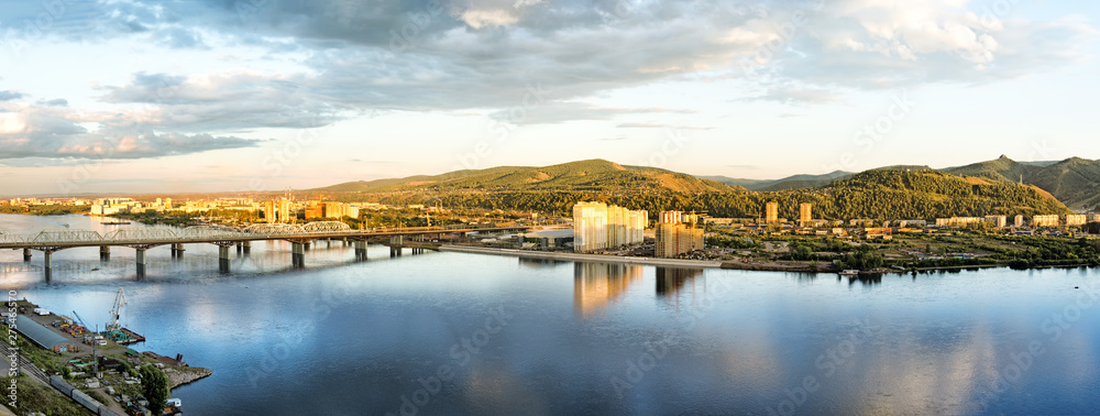 railroad bridge over Yenisei river at Krasnoyarsk city sunset panorama skyline landscape aerial view of russian siberian town cityscape with scenic Sayan mountains scenery surroundings at autumn