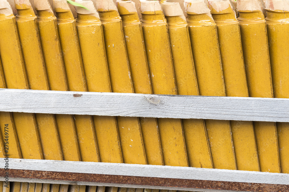Stacks of yellow ceramic glazed curved roof tiles in a symmetrical pattern.
