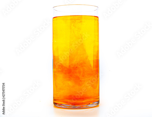 Orange food coloring diffuse in water inside tall glass with empty copyspace area for slogan or advertising text message, over isolated white background.