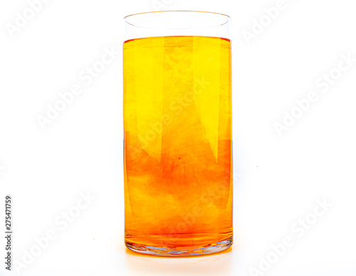 Orange food coloring diffuse in water inside tall glass with empty copyspace area for slogan or advertising text message, over isolated white background.