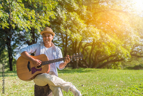Young asian man playing guitar in park