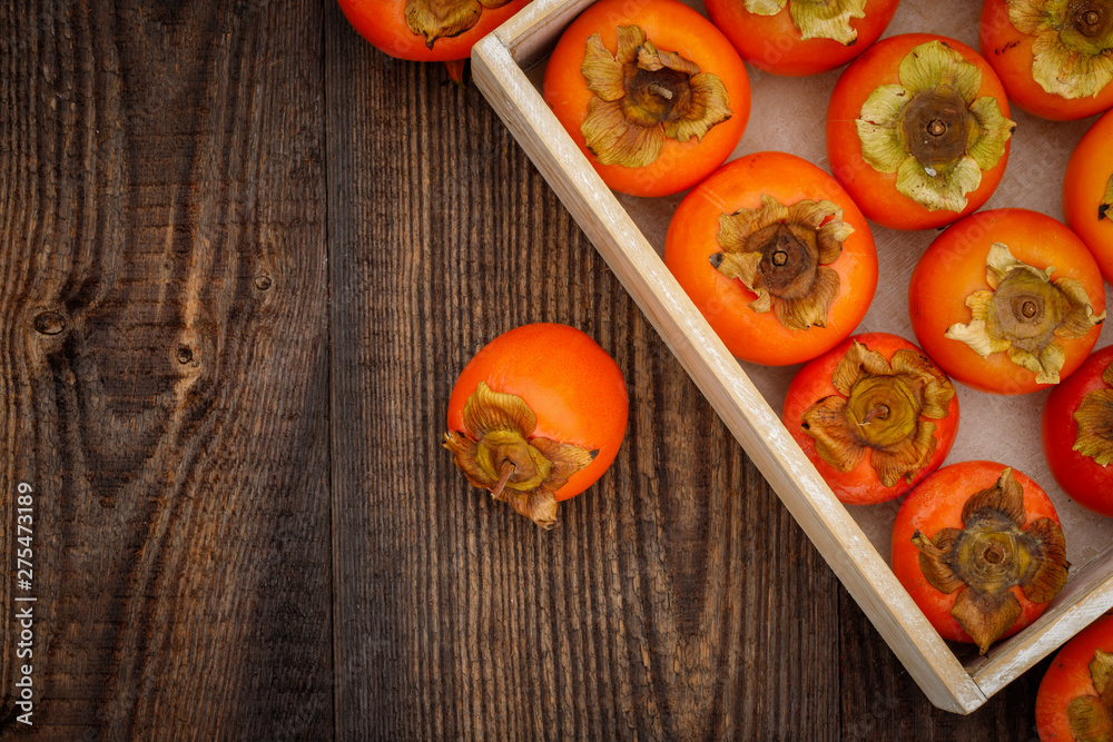 Ripe orange persimmon fruit on brown wooden table. Organic persimmon fruit  at market. Persimmons background with copy space, text place 