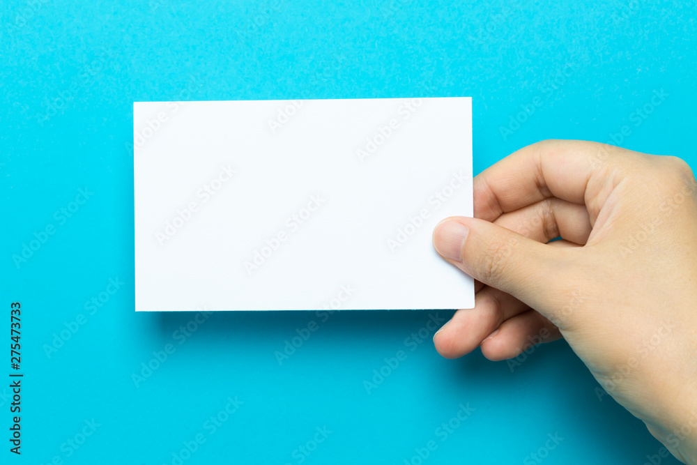 Hand holding up a note card on a blue background Hand holding up a note card on a blue background