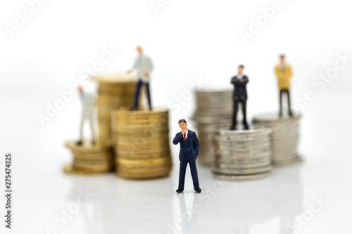 Miniature people:  Businessman standing on the stack of coins. Image use for business concept.