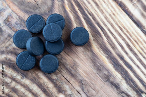 Close up black round pills on wooden table