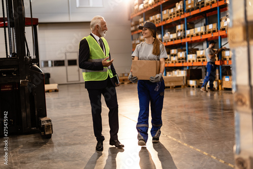 Happy senior businessman communicating with female distribution warehouse worker.