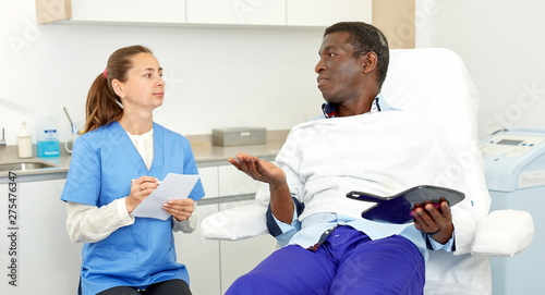 Man client having consultation with cosmetologist before procedure in clinic