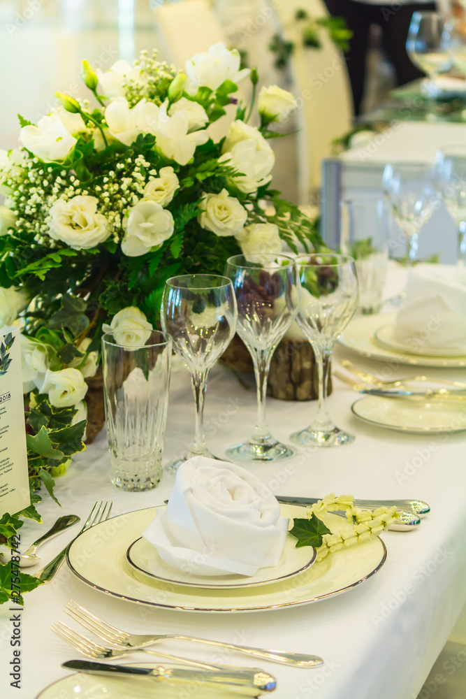 Fototapeta premium Wedding party dinner table setting with tableware and silverware and glasses set and Candlestick and flower in restaurant.