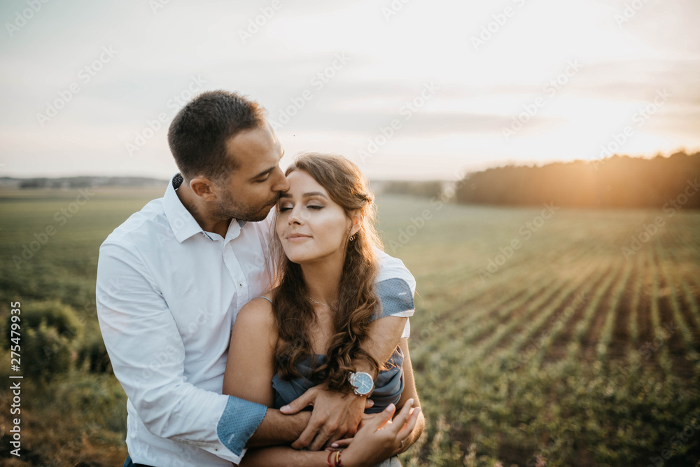 couple in love in a field at sunset in the summer smiling and happily hugging. engagement concept, weddings in nature. couple in love in a field at sunset in the summer smiling and happily hugging. engagement concept, weddings in nature.