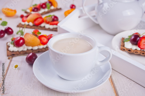 Cup of tea and crisp bread with creme cheese, fruit and berries