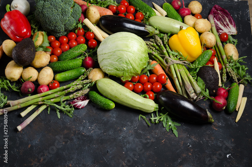 Top view portrait of Assortment of fresh raw vegetables on black wooden background with blank space.