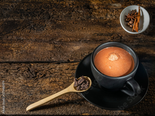 Cup of chocolate with spices and mortar on an authentic old table