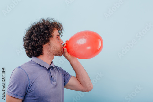 Fotografija young man inflates a red balloon