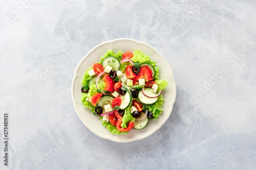 Greek salad. A plate of fresh salad with lettuce, feta cheese, tomatoes, cucumbers, onions and olives, shot from above with a place for text