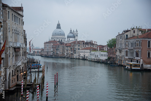 Grand Canal and the island of Santa Maria della Salute with the Dogana from the Accademia bridge in Venice, Italy. Widespread dawn light over the lagoon with a view of the houses and the ferry stop.