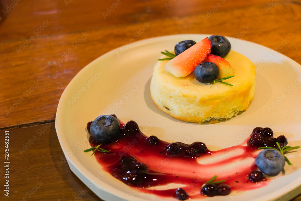 Homemade Blueberry and strawberry cheesecake on plate decoration with fresh fruit and jam, dessert on wooden table.