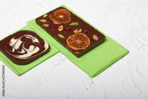 Homemade black chocolate. Decorated with slices of dried orange, strawberries, cherries and pistachios. On the surface covered with decorative plaster white.