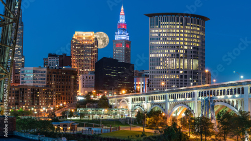 Big moon rising over skyline in small city America with bright lights and iconic bridge, Cleveland Ohio photo