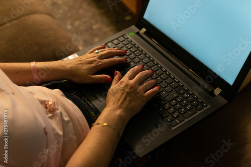 Partial close-up view of mature woman typing on laptop