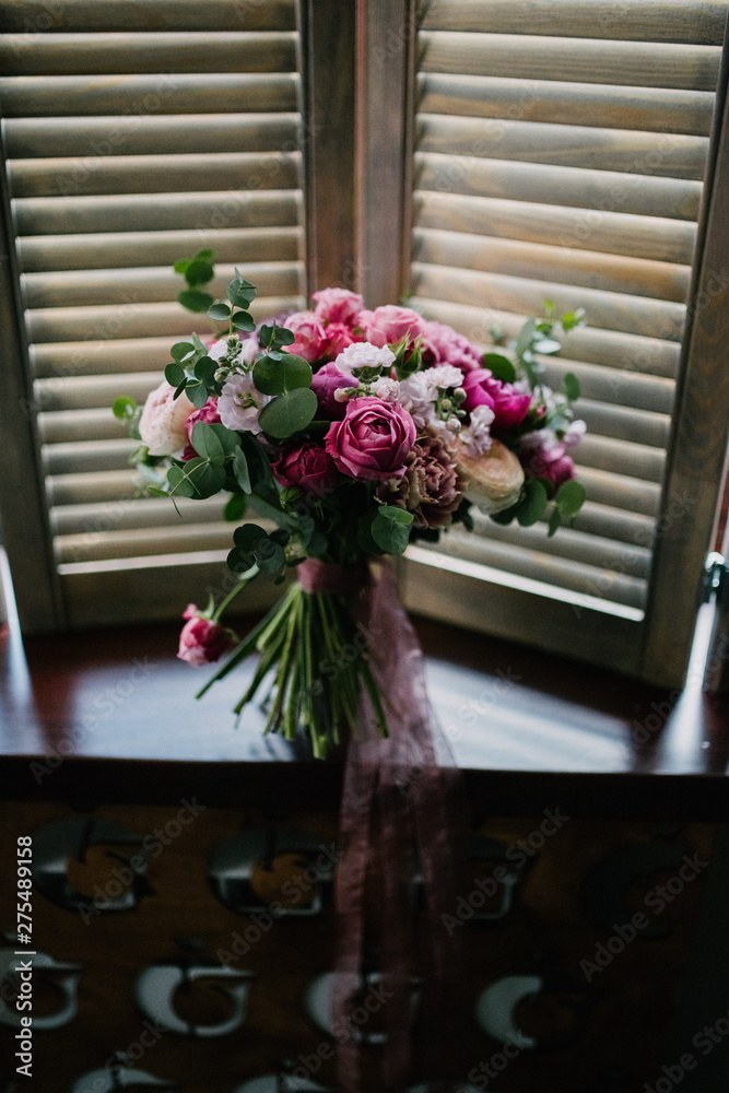 Fototapeta premium White bouquet of flowers standing in a vase on the window