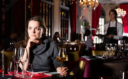 Young woman holding glass of white wine in luxurious restaurant