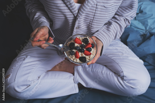 Top view of a woman sitting in bed. have a healthy Breakfast of oatmeal and berries