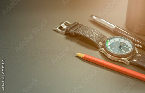 Close up shot of Stainless steel watch case, leather strap with pen and red pencil On black metal surface background.