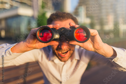 Happy business person looking through binoculars.