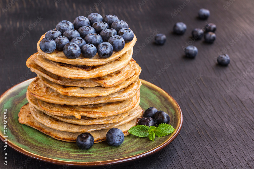 Delicious pancake with blгуberries in green dish on black table. Delicious pancake with blгуberries in green dish on black table.