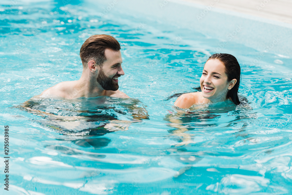 handsome bearded man looking at attractive woman in swimming pool handsome bearded man looking at attractive woman in swimming pool
