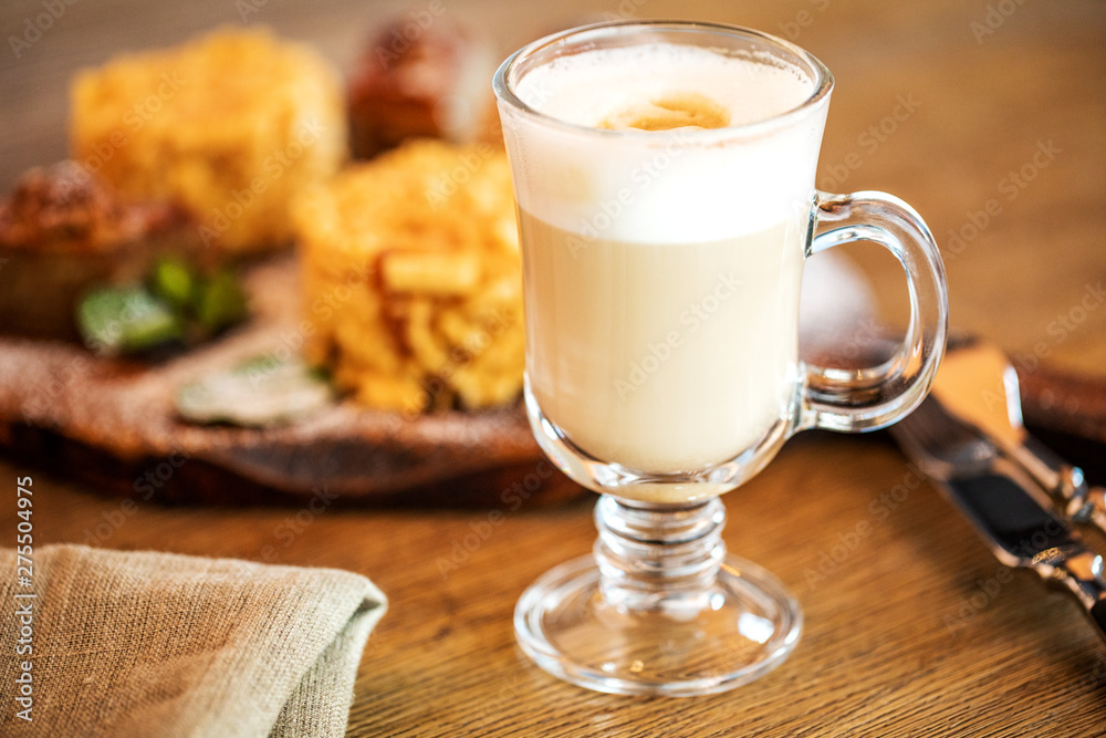 Cappuccino Cup with latte on wooden background. Beautiful foam, green ceramic Cup.