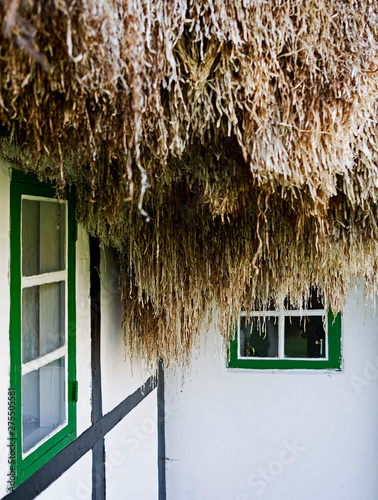 Laesoe / Denmark: Eaves of an old half-timbered farmhouse with green window frames and thatched with a seaweed roof