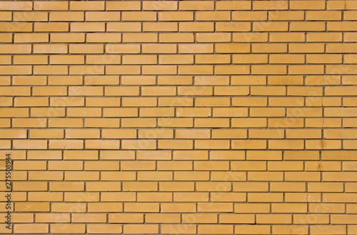 The brick wall of the building, made of light brown brick. Modern smooth brickwork.