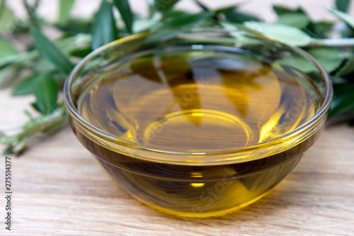 natural olive oil in glass container with olive branches