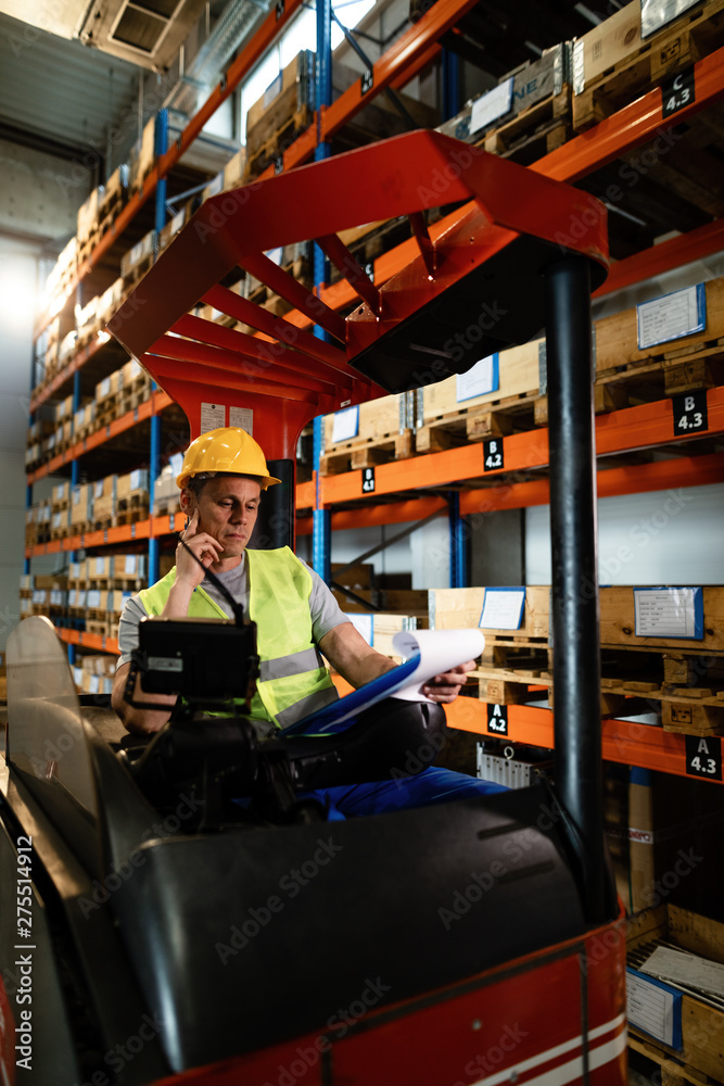 Forklift driver checking his daily schedule in a distribution warehouse.