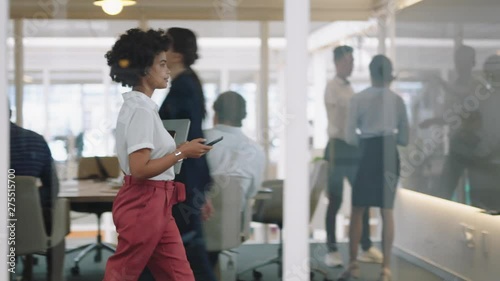 mixed race business woman using smartphone walking through office texting sending emails successful female executive checking messages on mobile phone arriving at busy workplace 4k  