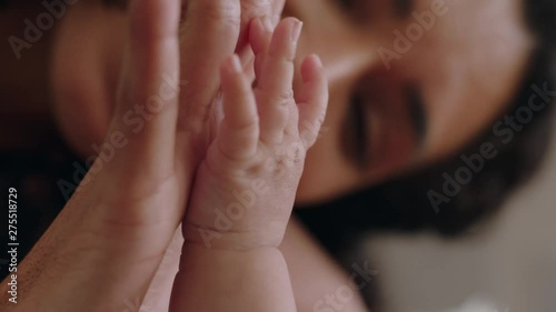 close up happy mother holding baby hand touching fingers nurturing newborn caring for infant enjoying motherhood connection with child photo