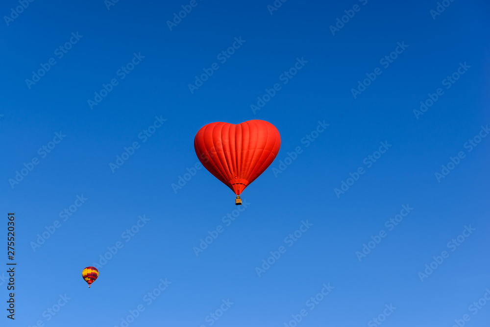 Fototapeta premium Red heart shaped balloon on the background blue sky.