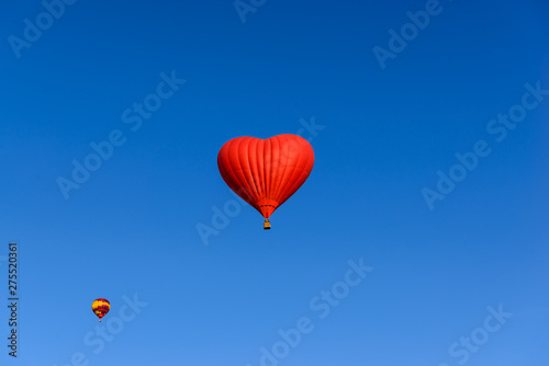 Red heart shaped balloon on the background blue sky. © 7707601